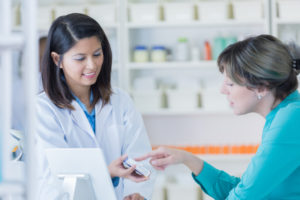 Female pharmacy customer talks with pharmacist about over the counter medication.