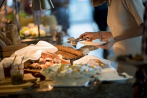 Woman filling her plate at a breakfast buffet.